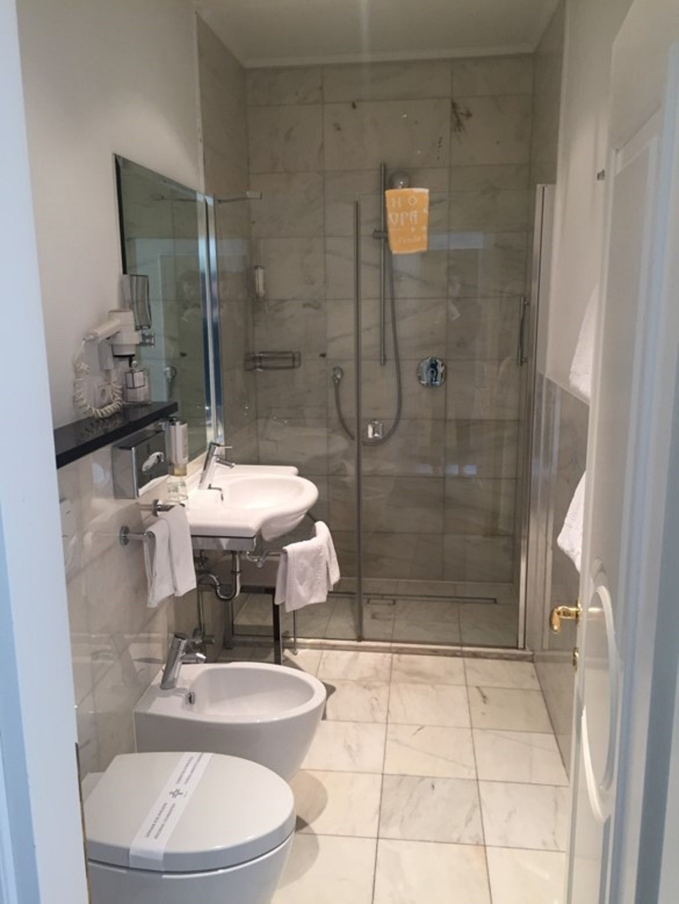 Un baño moderno con ducha acristalada, lavabo e inodoro.