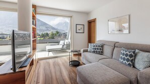 Un salon moderne avec un canapé, un téléviseur, une bibliothèque et une vue sur les montagnes.