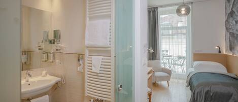 Una habitación de hotel moderna con baño, cama y vistas al exterior.