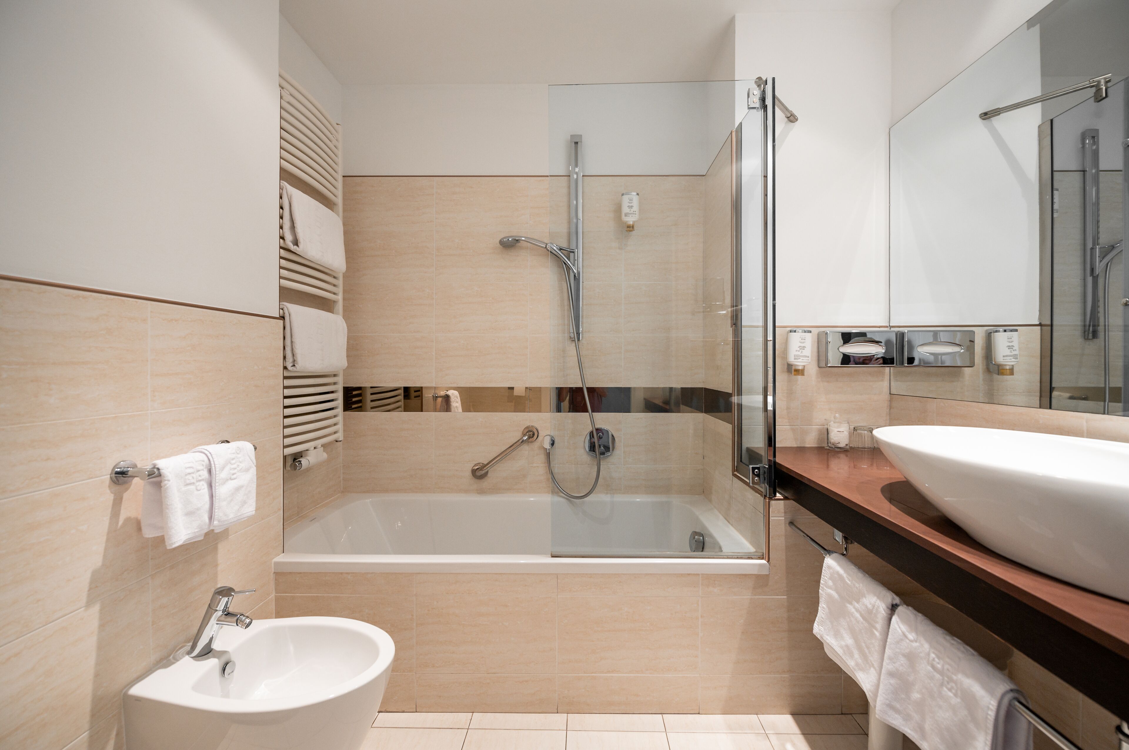 Un baño moderno con ducha envuelta en vidrio, una bañera independiente, un lavabo y un espejo grande.
