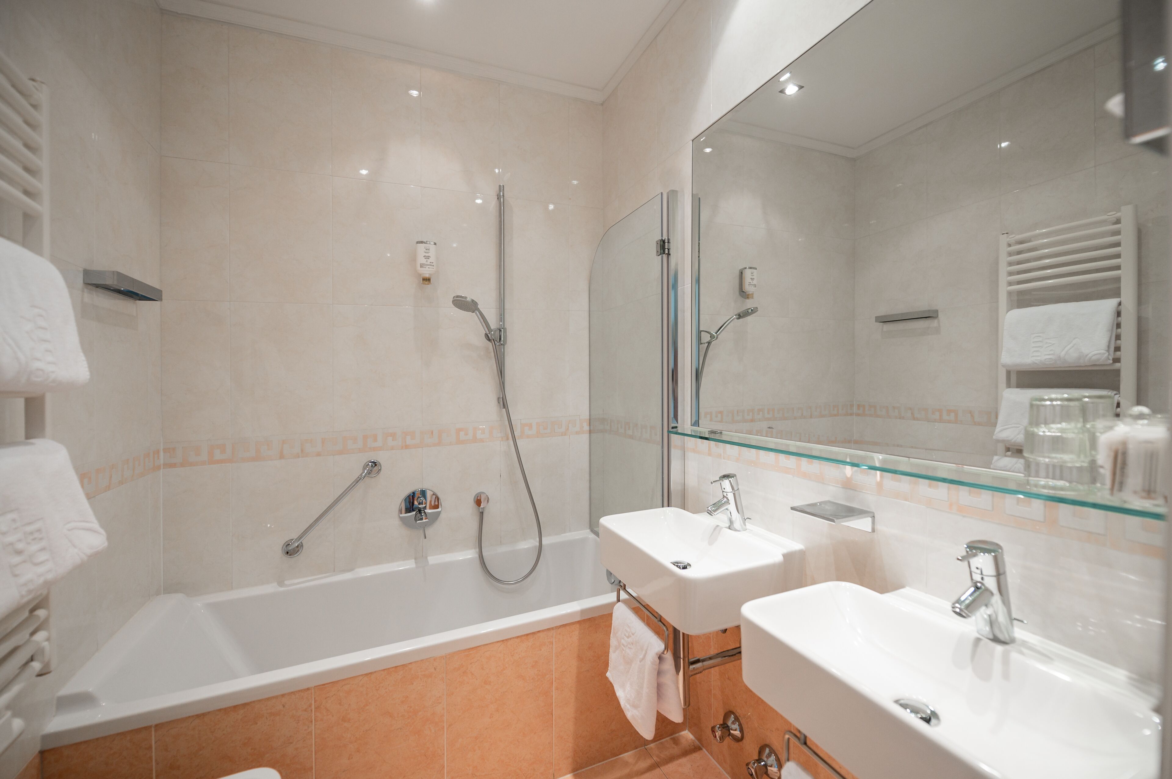 A modern bathroom with a glass shower enclosure, two sinks, and a large mirror.