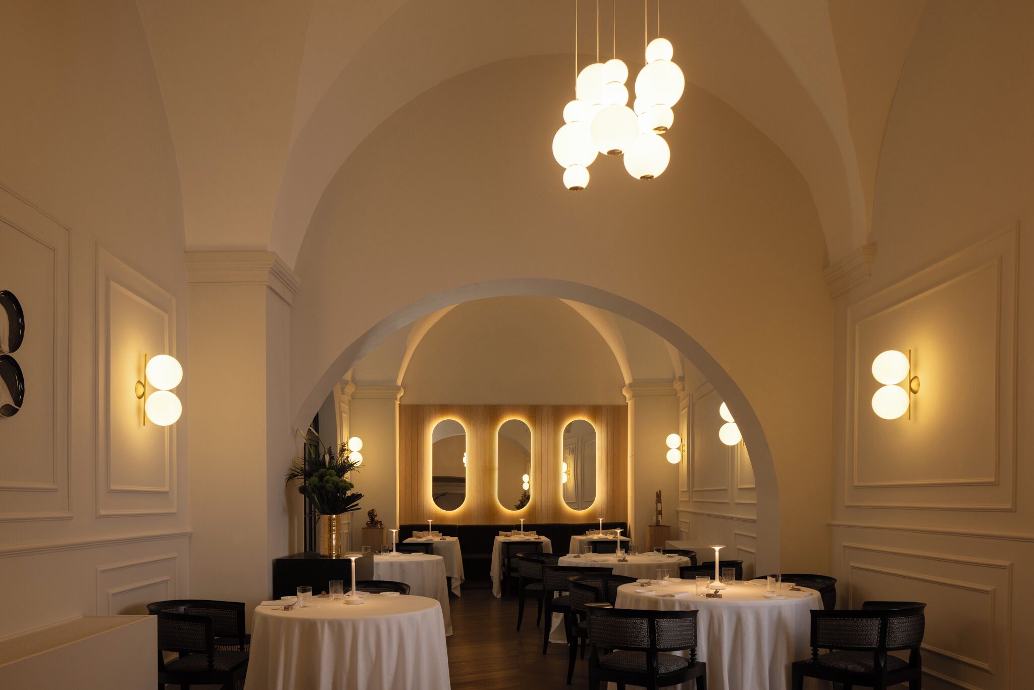 A dining area with round tables, chandeliers, and arched ceilings.