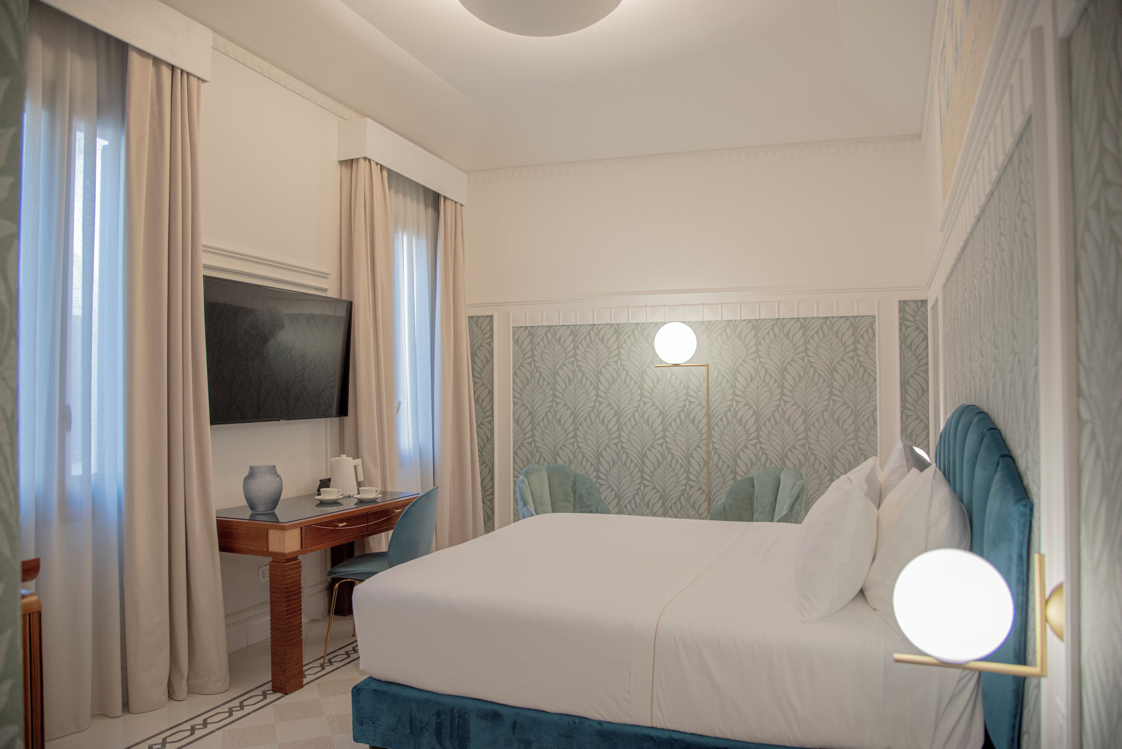Habitació d'hotel amb un llit gran, escriptori, cadira, televisió i un mirall fixat a la paret.