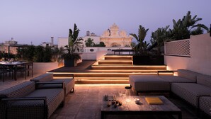 A rooftop patio with outdoor seating, a chessboard, and a view of a historic building in the background. - Patria Palace Hotel Lecce - Leading Hotels of the World (Lecce)