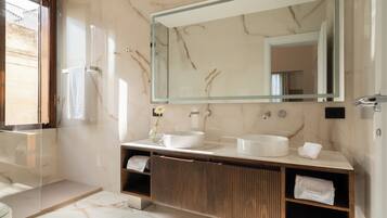 A modern bathroom with a large mirror, two sinks, a wooden vanity, and a towel rack.