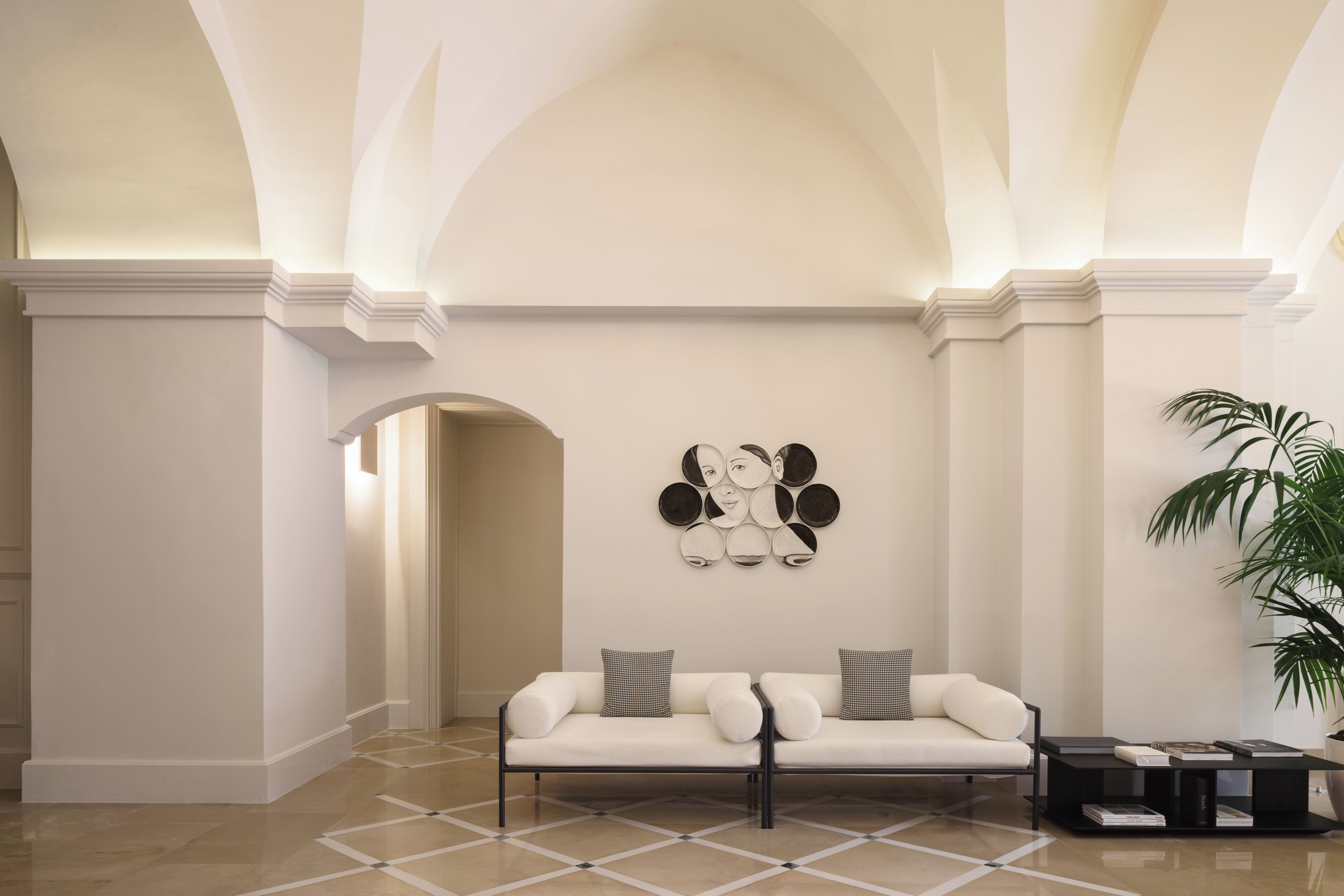 Una hall moderna con un divano bianco, un tavolino da caffè e un'opera d'arte a parete.