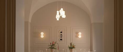 A dining area with a high arched ceiling, pendant lighting, and a table set for four with chairs.