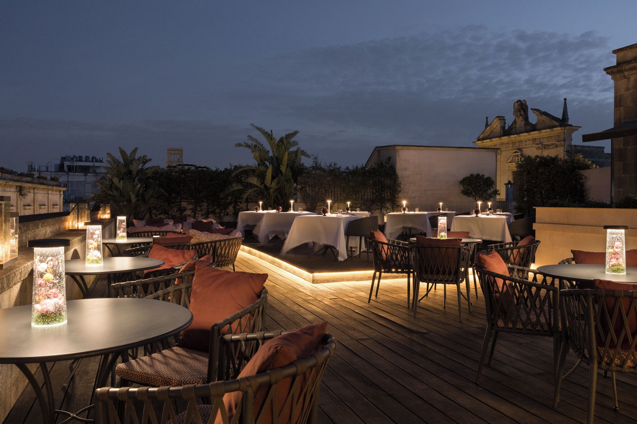 Un espace de restauration en plein air avec des tables et des chaises, une scène et une vue sur le paysage urbain au crépuscule.