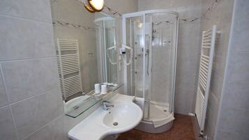 Une salle de bain avec une douche à parois de verre, un lavabo blanc et un porte-serviettes.