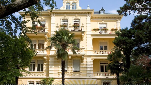 A multi-story building with balconies, large windows, and a yellow facade. - Hotel Westend (Merano)