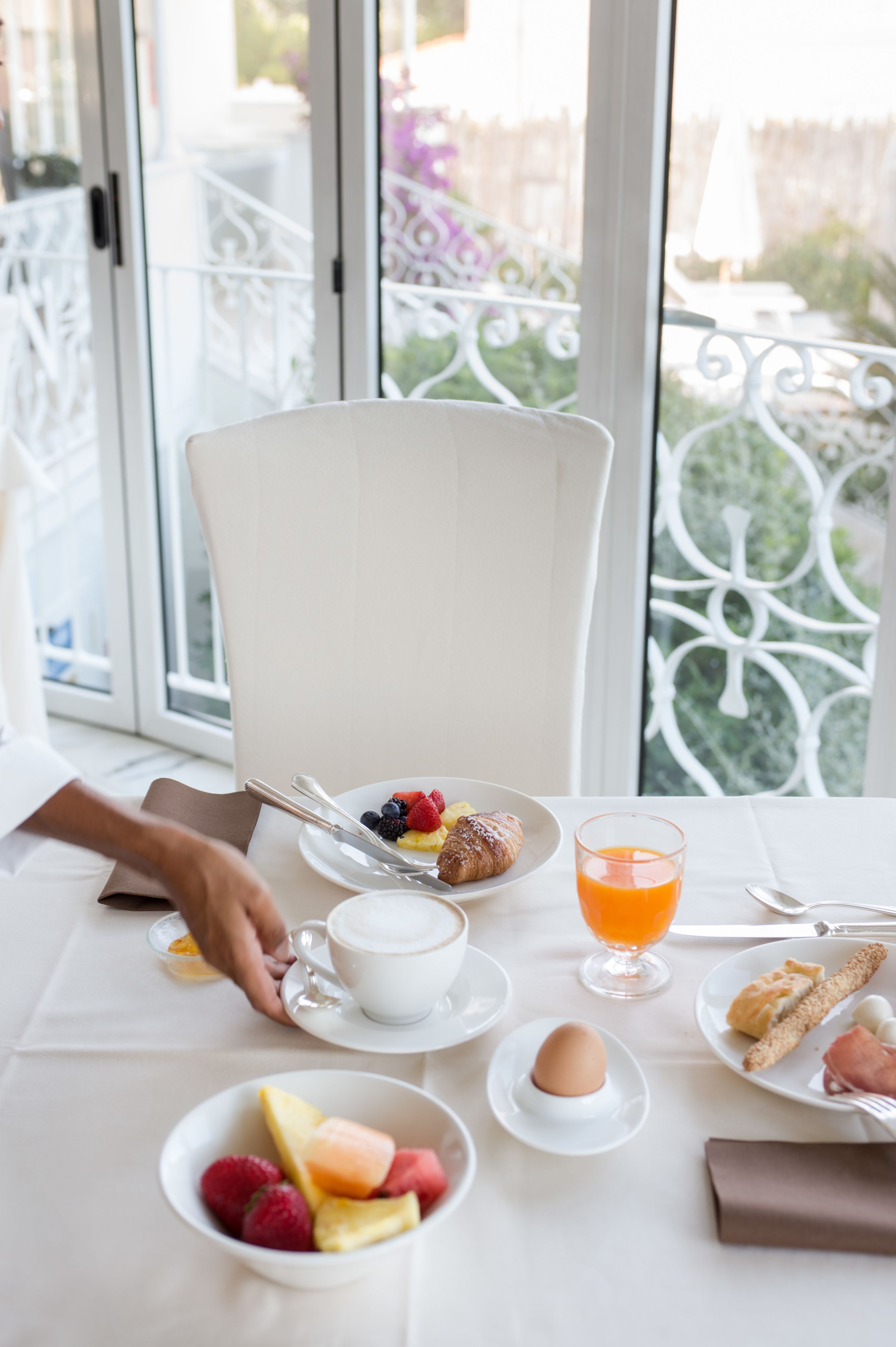 A breakfast setting with a table, plates of food, and a glass of orange juice.