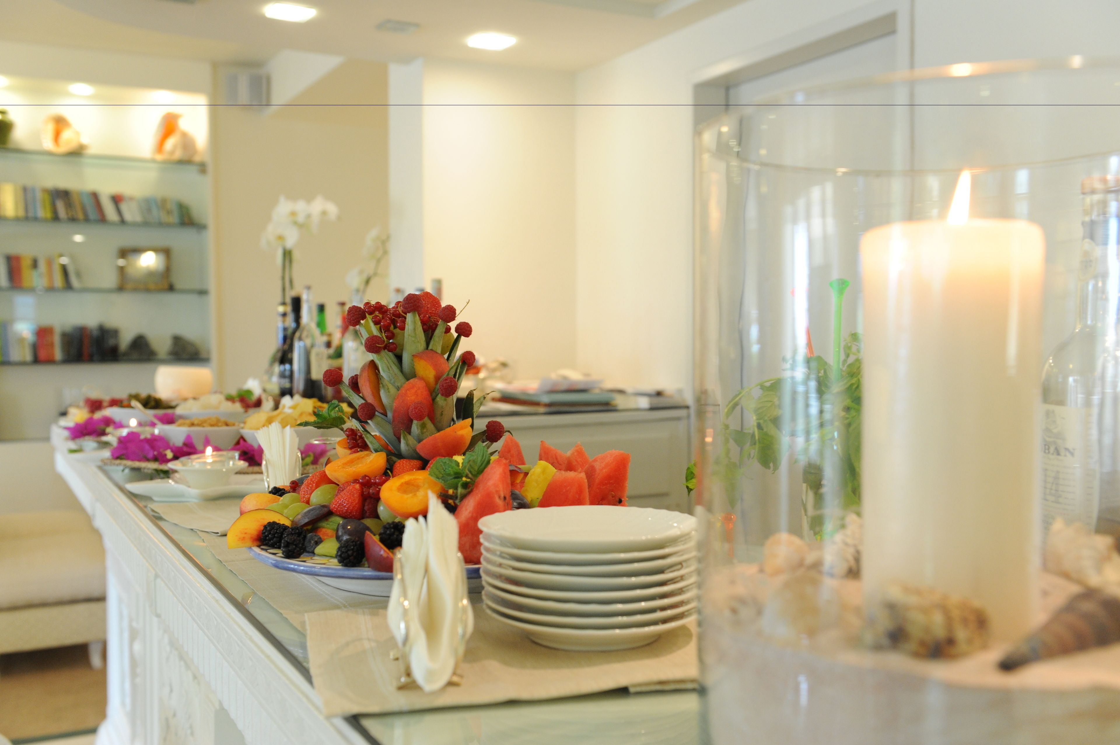 A buffet with various fruits and a candle.