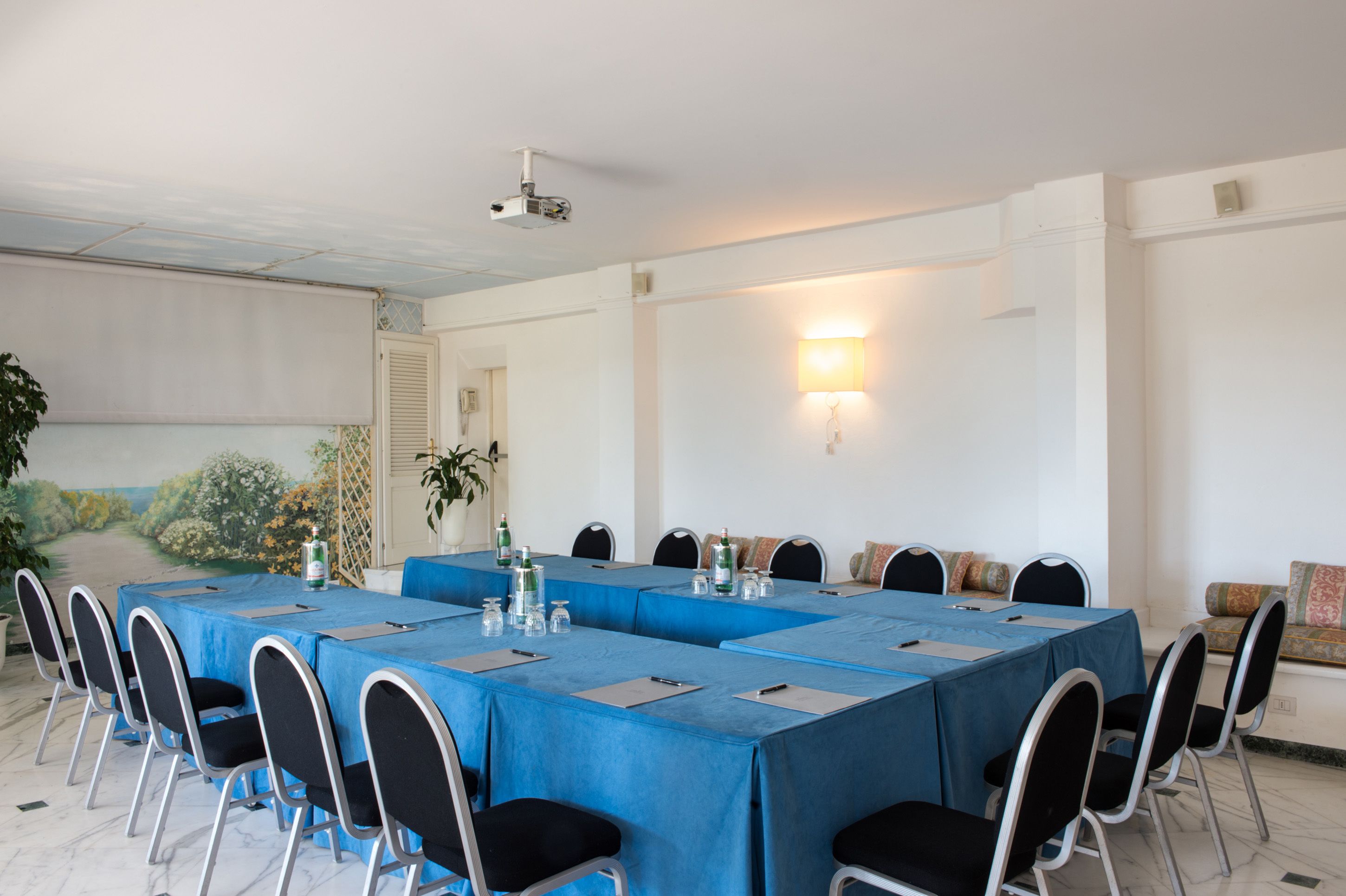 A conference room with a long table, chairs, and a projector.