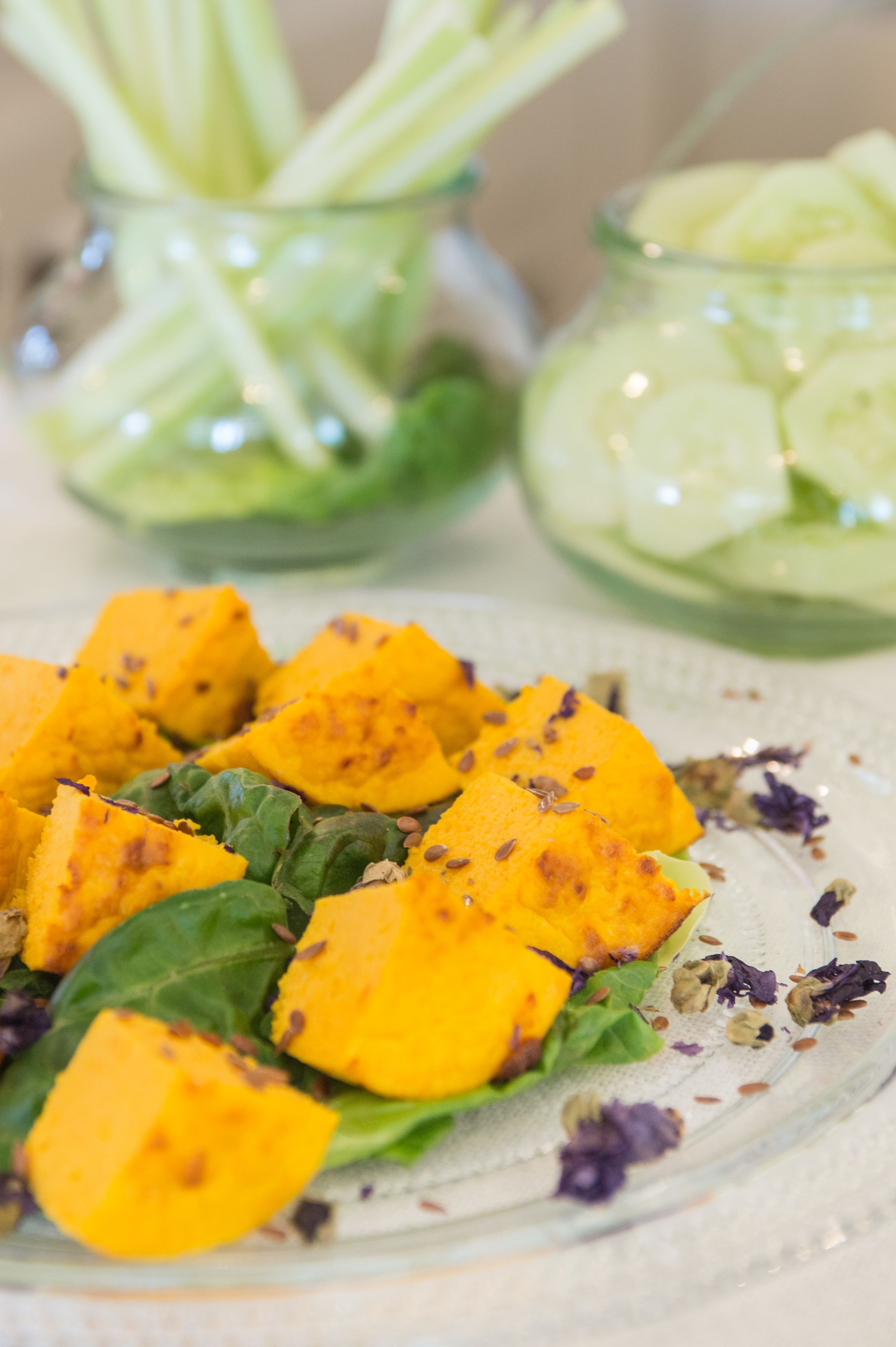 A glass plate with cubed mango salad, green leaves, and seeds.