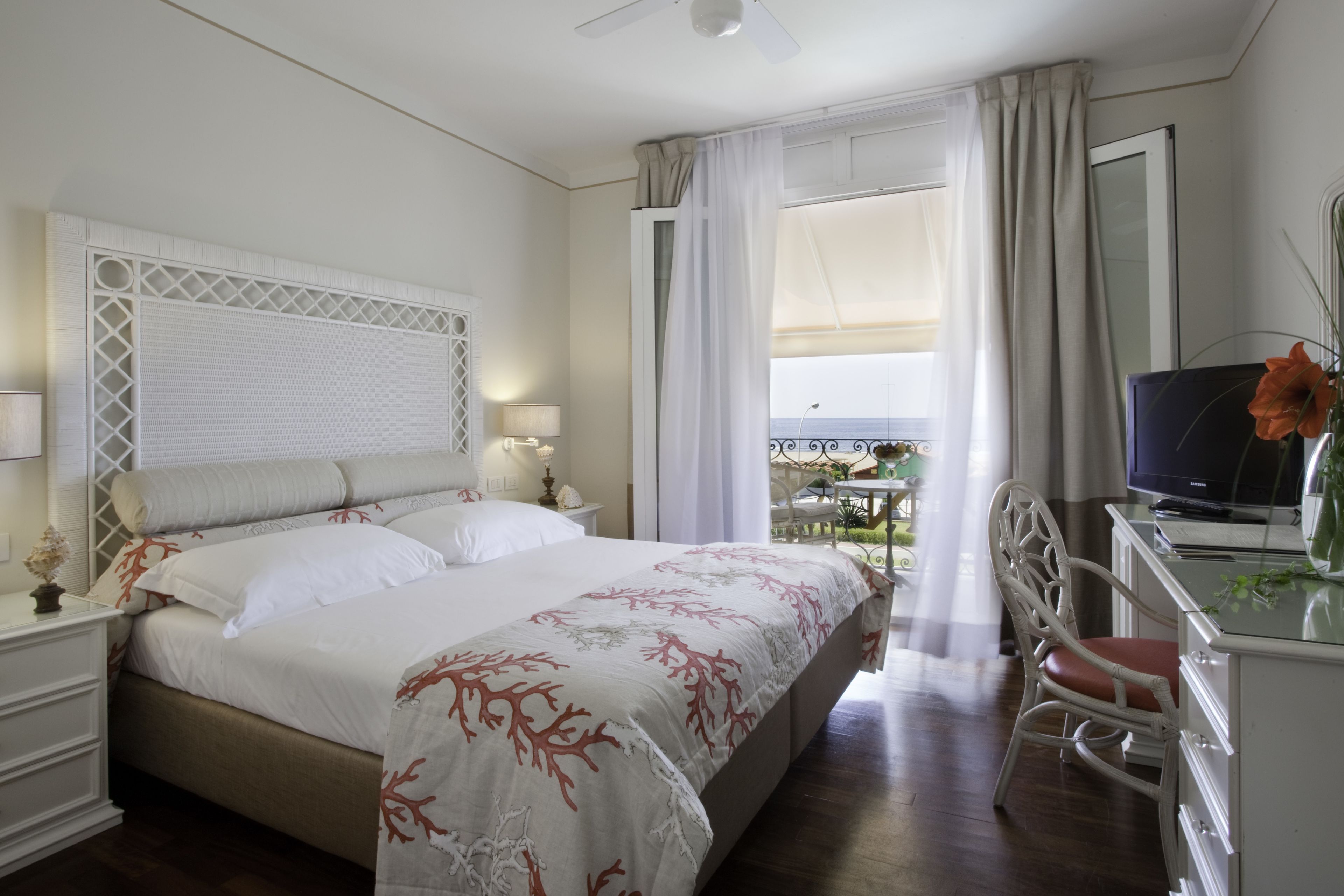 Una camera d'albergo con un letto grande, una scrivania con un computer e un balcone con vista.