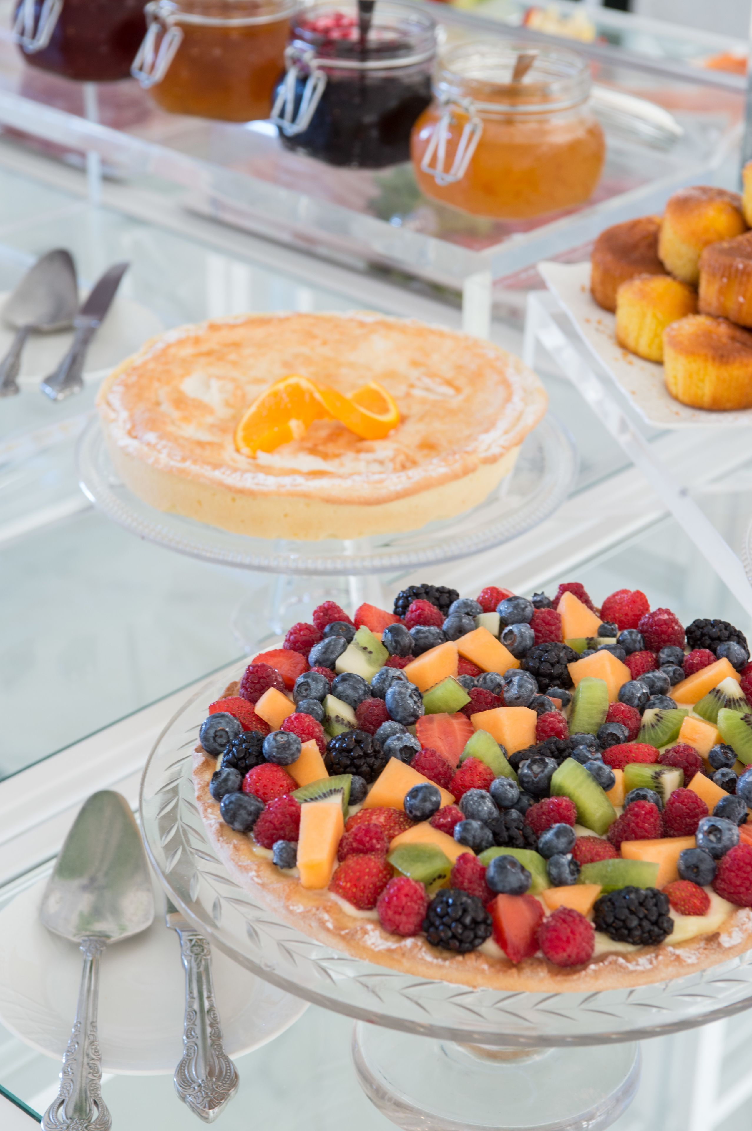 Ein Buffet mit einer Auswahl an Desserts und Früchten auf einer Glastheke.