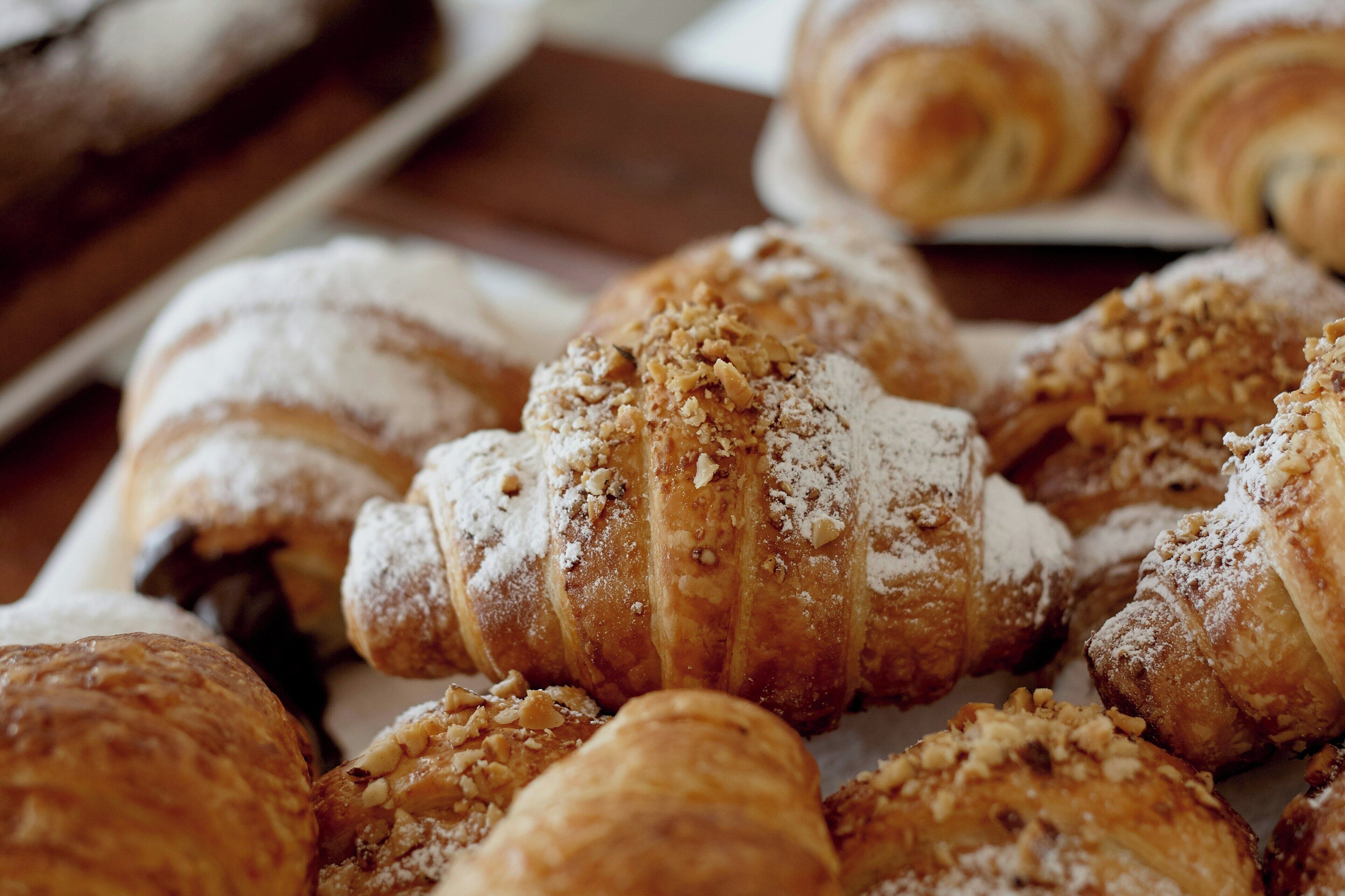 A variety of pastries, including croissants and pastries dusted with powdered sugar.