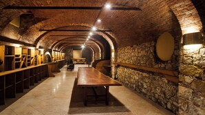 A long, narrow room with a high, arched brick ceiling and stone walls. There are wooden benches along one side and a long table in the center. - Kona Hotel Verona  (Negrar)