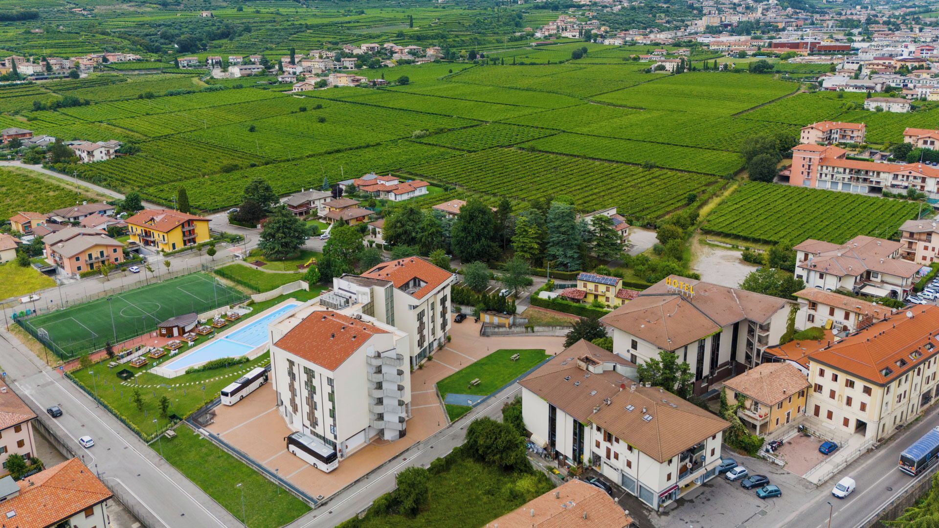 Un hotel con piscina, rodeado de campos verdes y edificios residenciales.