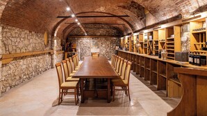 A long wooden table with chairs in a stone-walled room with a brick ceiling. - Kona Hotel Verona  (Negrar)