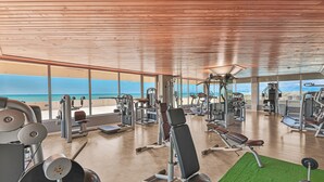 Un gimnasio con equipo de ejercicio diverso y vista al mar.