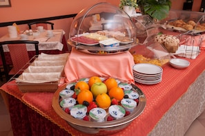 Un bufé de desayuno con diversas opciones de comida y una presentación de frutas.