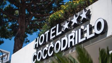 Segnaletica di un hotel con la scritta 'HOTEL COCODRILLO' e decorazioni a stelle e fiori.