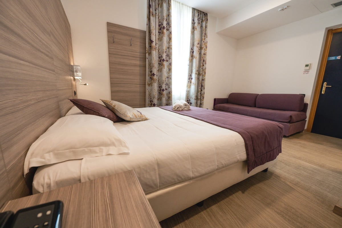 Ein modernes Hotelzimmer mit einem großen Bett, einer Couch und einem Holzkopfteil.