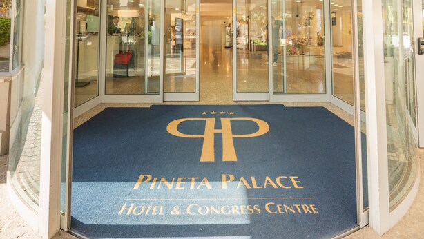 The entrance to Pineta Palace Hotel & Congress Centre with a blue carpet and a large logo. - Hotel Pineta Palace (Rome)