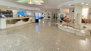 A modern hotel lobby with a reception desk, digital display, and a decorative ceiling feature. - Hotel Pineta Palace (Rome)