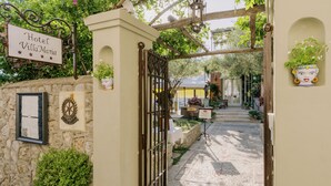 Un muro de piedra con un letrero que dice "Hotel Villa Maria" y una puerta que da a un patio.