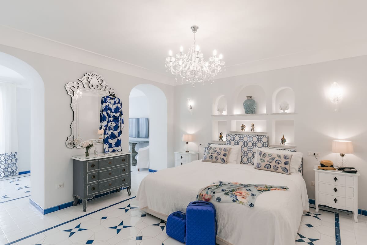 A bedroom with a large bed, a dresser, a vanity, and a chandelier.