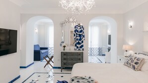 Una habitación de hotel con una cama grande, televisor, candelabro, cómoda y espejo.