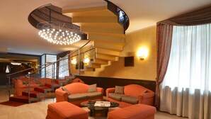A modern living room with a spiral staircase, orange furniture, and a chandelier. - Euro Motel (Nichelino)
