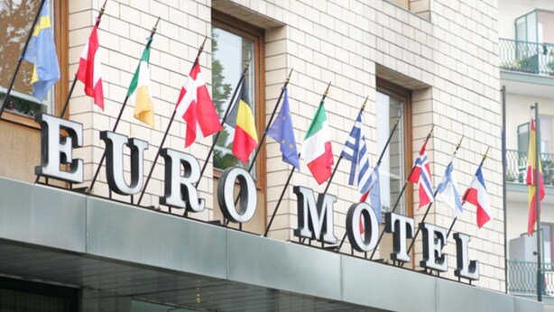 The exterior of the Euro Motel building with multiple flags displayed above the entrance. - Euro Motel (Nichelino)
