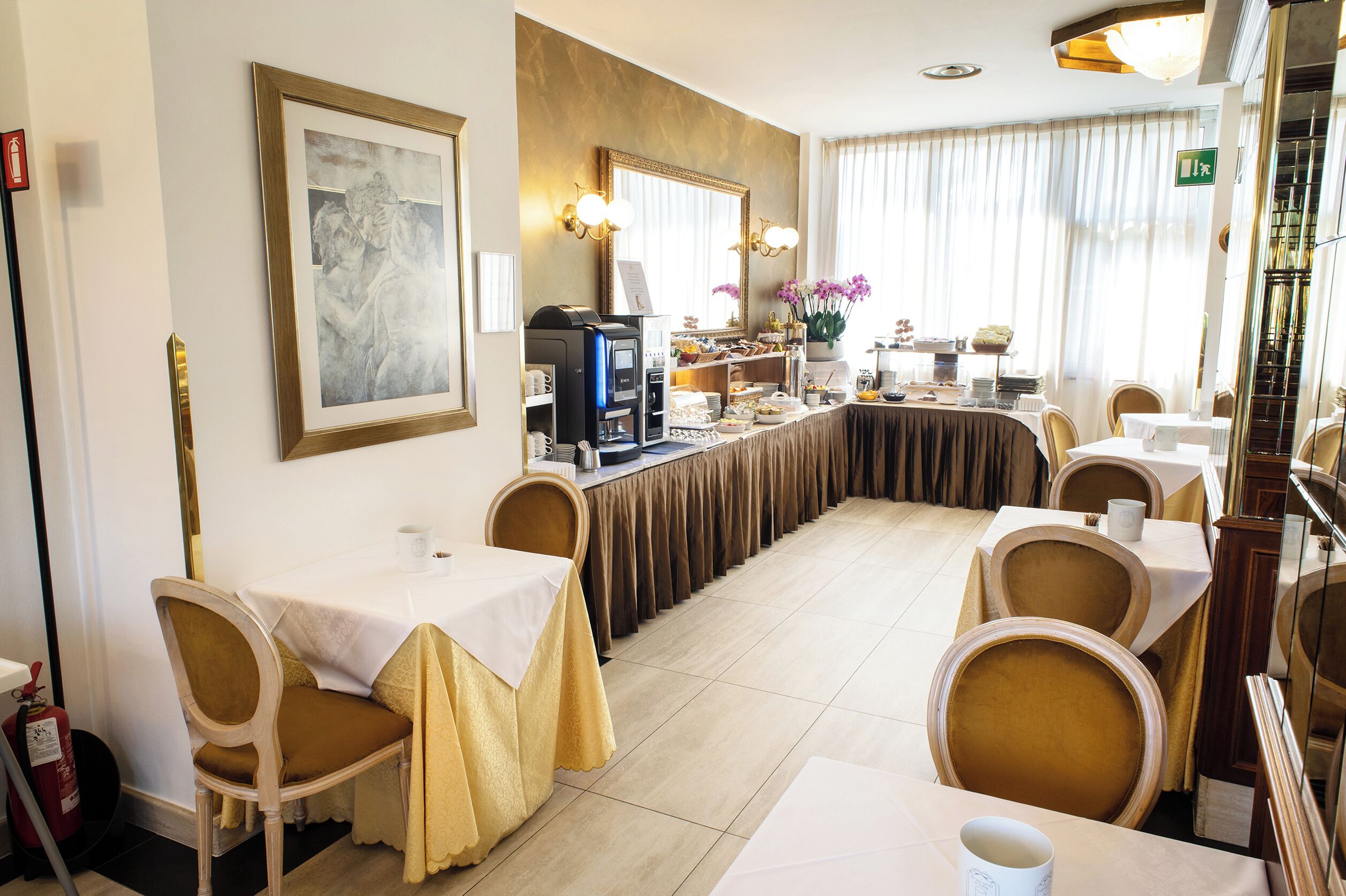 A hotel dining area with tables and chairs, a coffee machine, and a buffet setup.