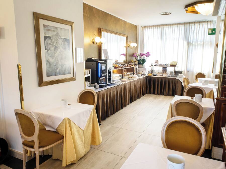 A hotel dining area with tables and chairs, a coffee machine, and a buffet setup.