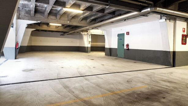 An empty parking garage with concrete floors, exposed beams, and emergency exits. - Hotel Alga (Milan)