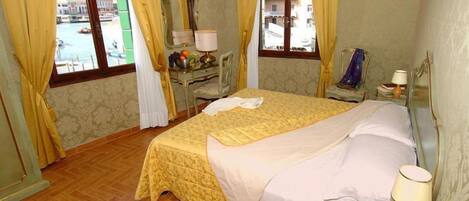 A hotel room with a bed, a desk with a lamp, a chair, and a window with curtains.