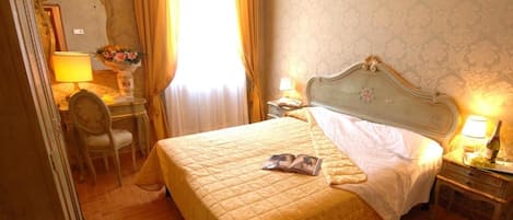 A hotel room with a bed, a desk, a chair, and a nightstand.