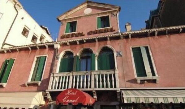 A hotel with a red awning and a balcony.