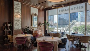 A restaurant with round tables, chairs, and a large window with a view of a building. - Hotel Dei Congressi (Rome)