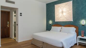 Une chambre à coucher bien rangée, avec un lit, des tables de chevet et un luminaire fixé au mur.