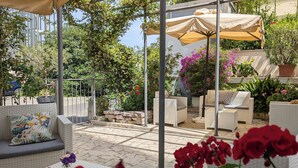 An outdoor patio area with wicker furniture, a pergola with a canopy, and various potted plants. - Hotel Dei Congressi (Rome)