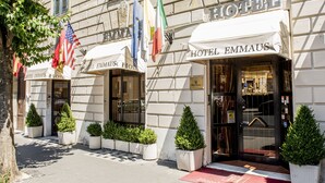 L’entrée d’un hôtel, avec un tapis rouge, des plantes en pot et des drapeaux.