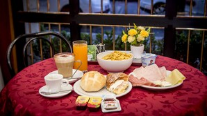 Une table de petit-déjeuner avec une variété d’aliments, notamment des céréales, des viennoiseries et une tasse de café.
