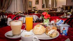 Une table dressée pour le petit-déjeuner, avec une tasse de café, un verre de jus d’orange, un croissant et une pâtisserie.