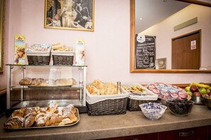 A breakfast buffet with various pastries, bread, and fruits.