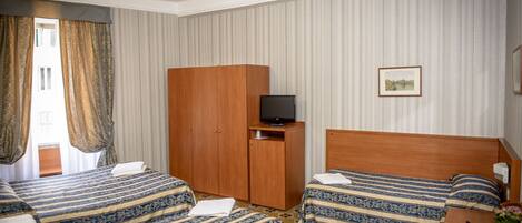 Habitación de hotel con dos camas, un armario de madera, un televisor y un escritorio con una computadora portátil.