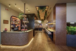Zona de bar con barra, estantes llenos de botellas y plantas colgantes.